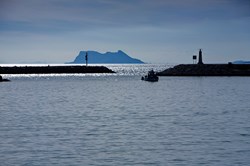 A fishing vessel entering the port of Estepona with a view to Gibraltar in the background
