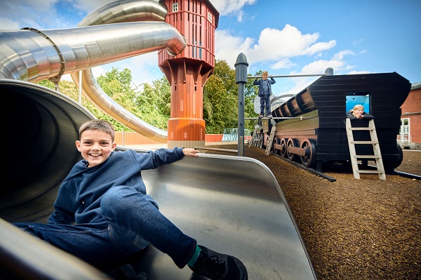 A boy is playing outside on the playground at the Danish Railway Museum