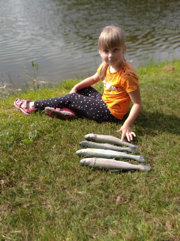 A girl sits on the grass next to several fish