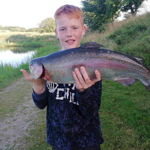 A boy holds a large fish in his hands