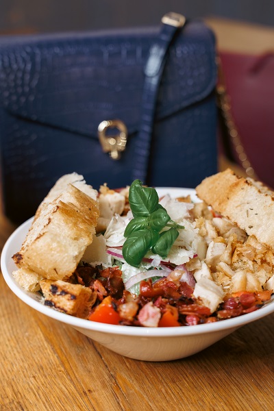  A bowl of salad with a handbag in the background