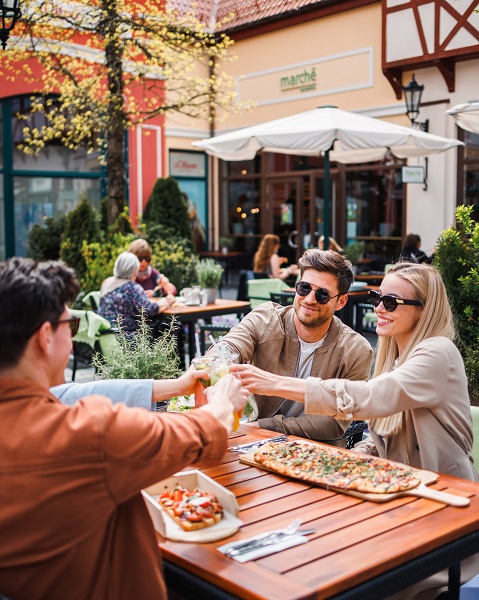 Two couples toast and eat pizza at the Designer Outlet Neumünster