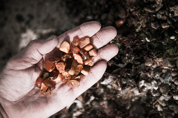 One hand holds a large number of small amber stones