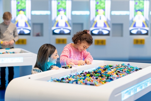 A little girl is building with LEGO® bricks together with her mother in the LEGO® House