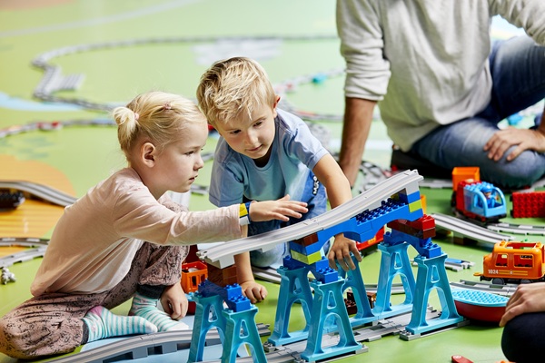 A boy and a girl are playing with a DUPLO® train in the LEGO® House