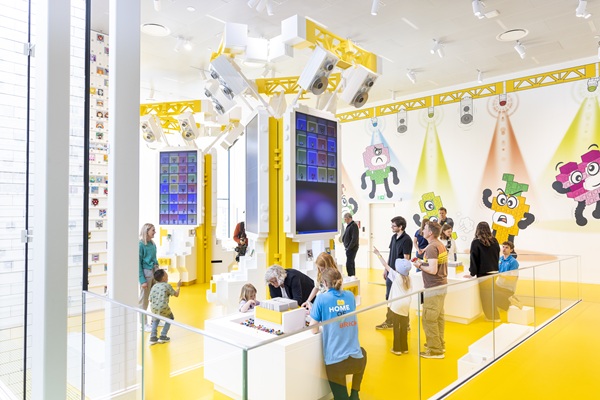 Children and adults are exploring the Yellow Zone in the LEGO® House