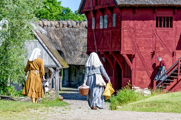 Two women from the Middle Ages carry laundry through the village