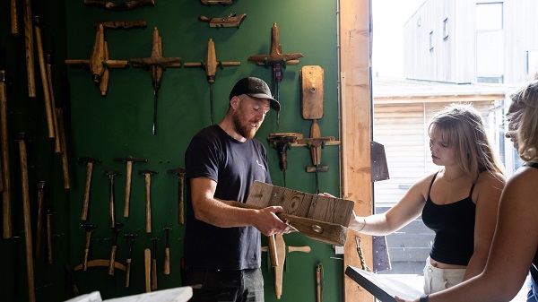 A man shows a wooden tool to a group of women in the workshop at the Viking Ship Museum in Roskilde