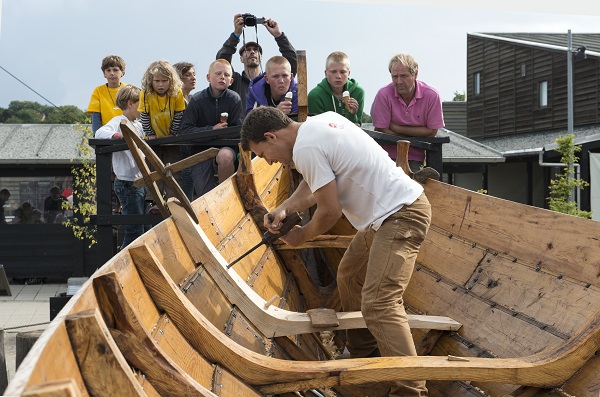 A man working on a wooden Viking ship at the Viking Ship Museum in Roskilde