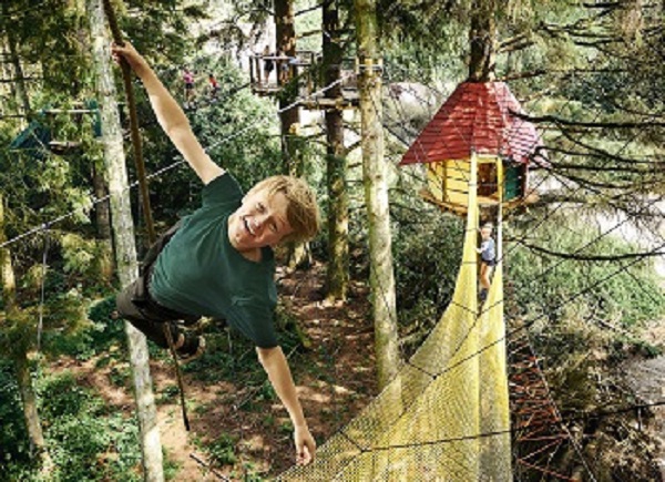 A young boy hangs from a climbing rope in WOW PARK